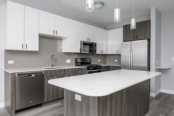 a kitchen with a white counter top and a stainless steel refrigerator